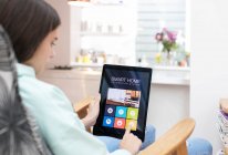Chica utilizando el sistema de automatización del hogar inteligente en tableta digital - foto de stock