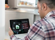 Hombre configuración inteligente alarma de seguridad del hogar de la tableta digital en la cocina - foto de stock