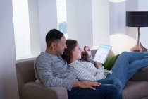 Пара розслабляється, використовуючи цифровий планшет на дивані у вітальні — стокове фото