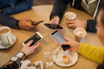 Young adult friends using smart phones and drinking coffee in cafe — Stock Photo