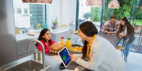 Família conversando, usando tablets digitais na cozinha — Fotografia de Stock