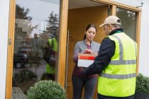 Woman signing for package from deliveryman at front door — Stock Photo