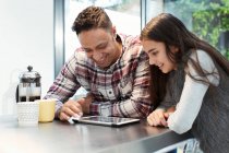 Smiling father and daughter using digital tablet at kitchen counter — Stock Photo