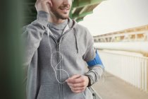 Мужчина бегун слушает музыку с наушниками и mp3-плеером — стоковое фото