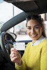 Portrait happy young woman holding new drivers license in car — Stock Photo