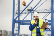 Hafenarbeiter mit Walkie-Talkie und Klemmbrett in der Werft — Stockfoto