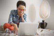 Sorrindo jovem Mulher usando laptop na cama — Fotografia de Stock