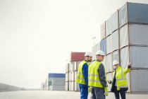 Hafenarbeiter und Manager unterhalten sich an Frachtcontainern auf der Werft — Stockfoto
