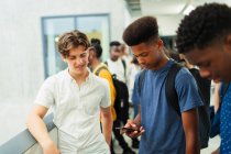 Молодші школярі використовують смартфон в коридорі — стокове фото