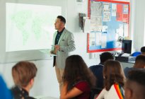 Преподаватель старшей школы проводит урок географии на проекционном экране в классе — стоковое фото