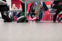 Pernas de estudantes universitários comunitários debaixo de mesas em sala de aula — Fotografia de Stock