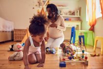 Pregnant mother and daughter playing with toys — Stock Photo