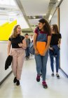 Junior high girl students walking and talking in corridor — Stock Photo
