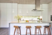 Modern white kitchen with island and barstools — Stock Photo