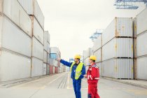 Trabajadores portuarios hablando entre contenedores de carga en el astillero - foto de stock