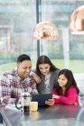 Happy father and daughters using digital tablet in morning kitchen — Stock Photo