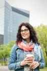 Donna sorridente che beve caffè nel parco urbano — Foto stock