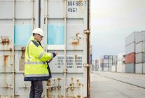 Trabalhador portuário que verifica contentores de carga no estaleiro — Fotografia de Stock