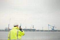 Trabajador portuario con walkie-talkie en muelle comercial - foto de stock