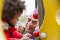 Lächelnder Opa spielt mit Enkel auf Spielplatz — Stockfoto