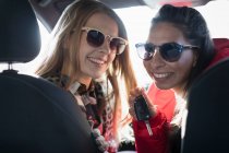 Retrato feliz jovens mulheres usando óculos de sol no carro — Fotografia de Stock