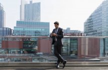 Uomo d'affari che utilizza smartphone sul balcone urbano soleggiato, Shoreditch, Londra — Foto stock