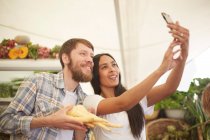 Lächelndes Paar macht Selfie auf Bauernmarkt — Stockfoto
