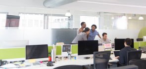 Gente de negocios hablando, reuniéndose en la computadora en la oficina abierta - foto de stock