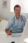Портрет уверенный мужчина врач, работающий за компьютером в кабинете врача — стоковое фото