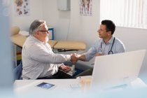 Maschio medico stringendo la mano con il paziente anziano in ufficio medici — Foto stock