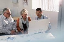 Doctor meeting with senior couple at computer in doctors office — Stock Photo
