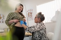 Médica examinando mulher grávida em consultório médico — Fotografia de Stock