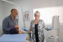 Técnico realizando ultrasonido para pareja embarazada en sala de examen - foto de stock