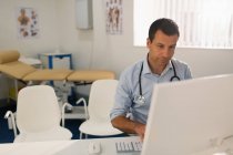 Médico do sexo masculino trabalhando no computador em consultório de médicos — Fotografia de Stock
