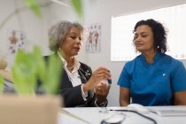 Female doctor teaching diabetic patient how to use glucometer in doctors office — Stock Photo