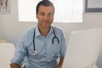 Porträt selbstbewusster männlicher Arzt, der in Arztpraxis am Computer arbeitet — Stockfoto