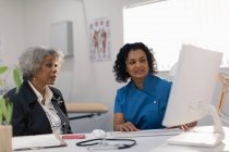 Female doctor meeting with senior patient at computer in doctors office — Stock Photo