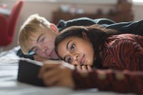Teenie-Paar legt sich mit Smartphone ins Bett — Stockfoto