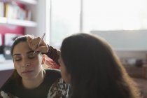 Teenage girl applying eyeshadow makeup to friends eye — Stock Photo