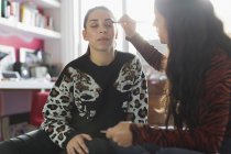 Teenage girl applying eyeshadow makeup to friends eyes — Stock Photo