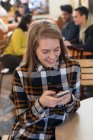 Молодая женщина, использующая смартфон в кафе — стоковое фото