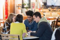 Young friends using smart phones at cafe table — Stock Photo