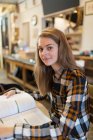 Портрет уверенной молодой студентки колледжа, обучающейся в кафе — стоковое фото