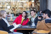 Young friends hanging out and studying at sidewalk cafe — Stock Photo