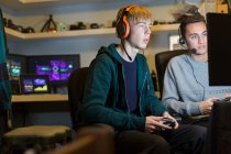 Adolescentes com fones de ouvido jogando videogame no computador no quarto escuro — Fotografia de Stock