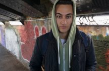 Portrait serious, tough young man wearing hoody in urban tunnel — Stock Photo