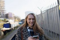 Jovem mulher usando telefone inteligente ao longo do canal — Fotografia de Stock