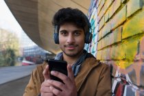 Портрет уверенный молодой человек, слушающий музыку с наушниками и mp3 плеером — стоковое фото