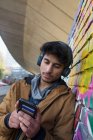 Молодой человек слушает музыку с наушниками и mp3-плеером — стоковое фото