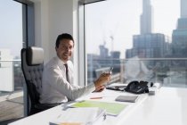Portrait confident businessman using smart phone in highrise office — Stock Photo